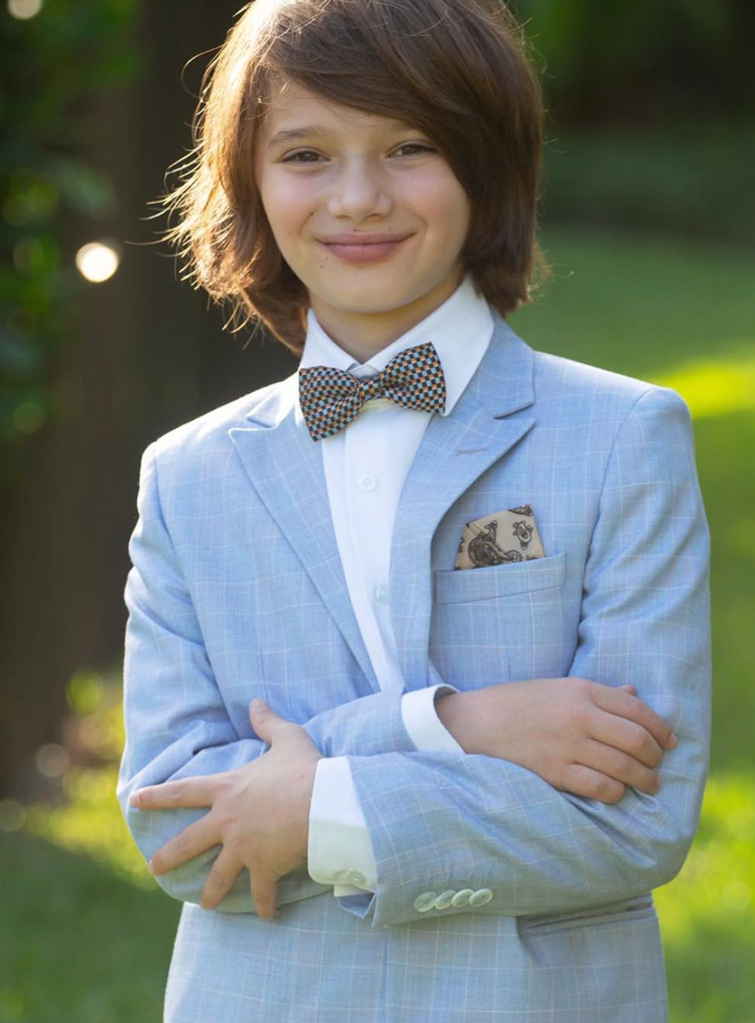 boy wearing sky blue blazer, with bow tie, and pocket square