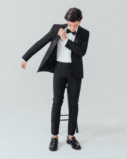 Teen adjusting his black tuxedo 