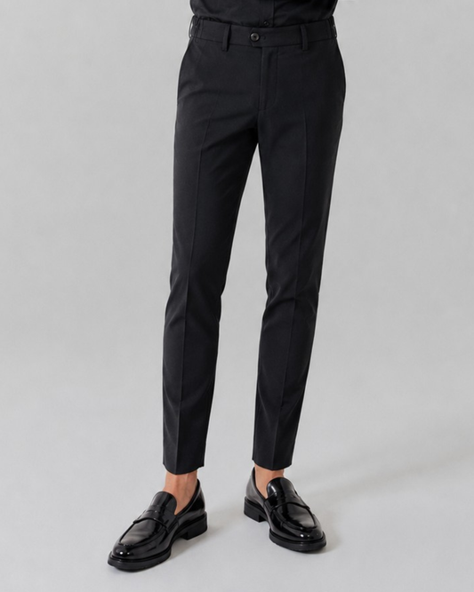 Black dress pants worn by a person on a gray background