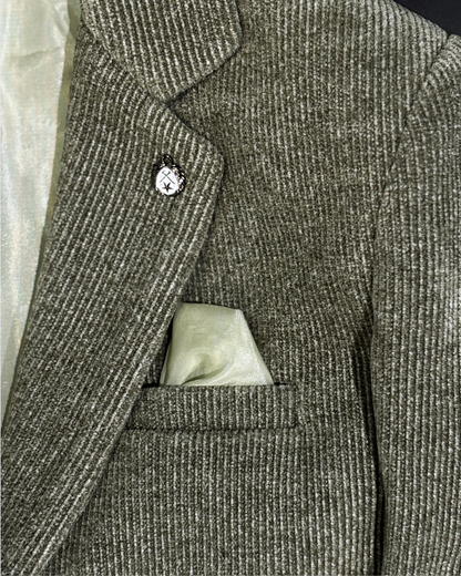 Close-up of olive corduroy blazer fabric showing textured ribbed pattern with built-in pocket square and lapel pin detail