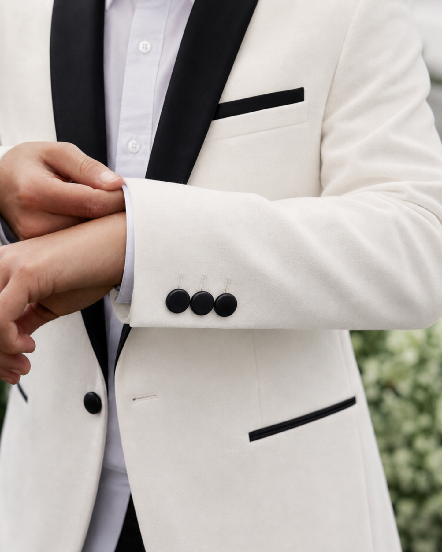 Close-up of a person wearing a white tuxedo with black lapels and buttons.