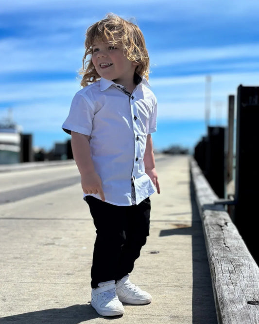 Boy wearing short sleeves shirt and chinos, standing on a pier