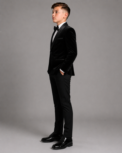 Boy wearing a black velvet suit against a grey background