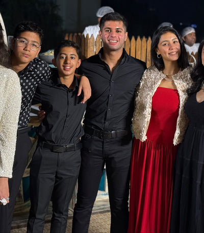 2 boys wearing a black shirt and black pants standing with other people in formal outfits