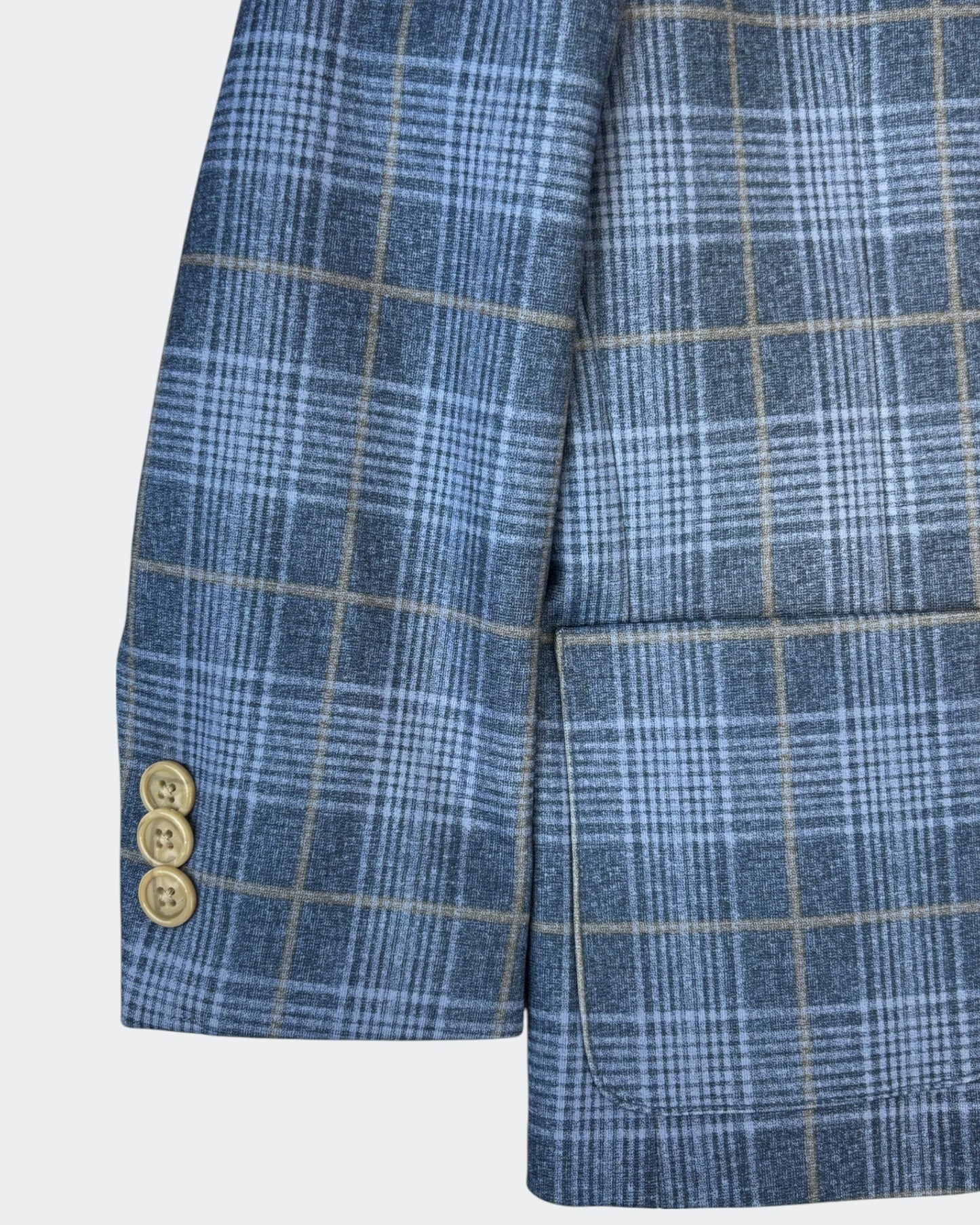 Close-up of a blue and grey plaid blazer sleeve with light brown windowpane checks, featuring three beige buttons and a front flap pocket.