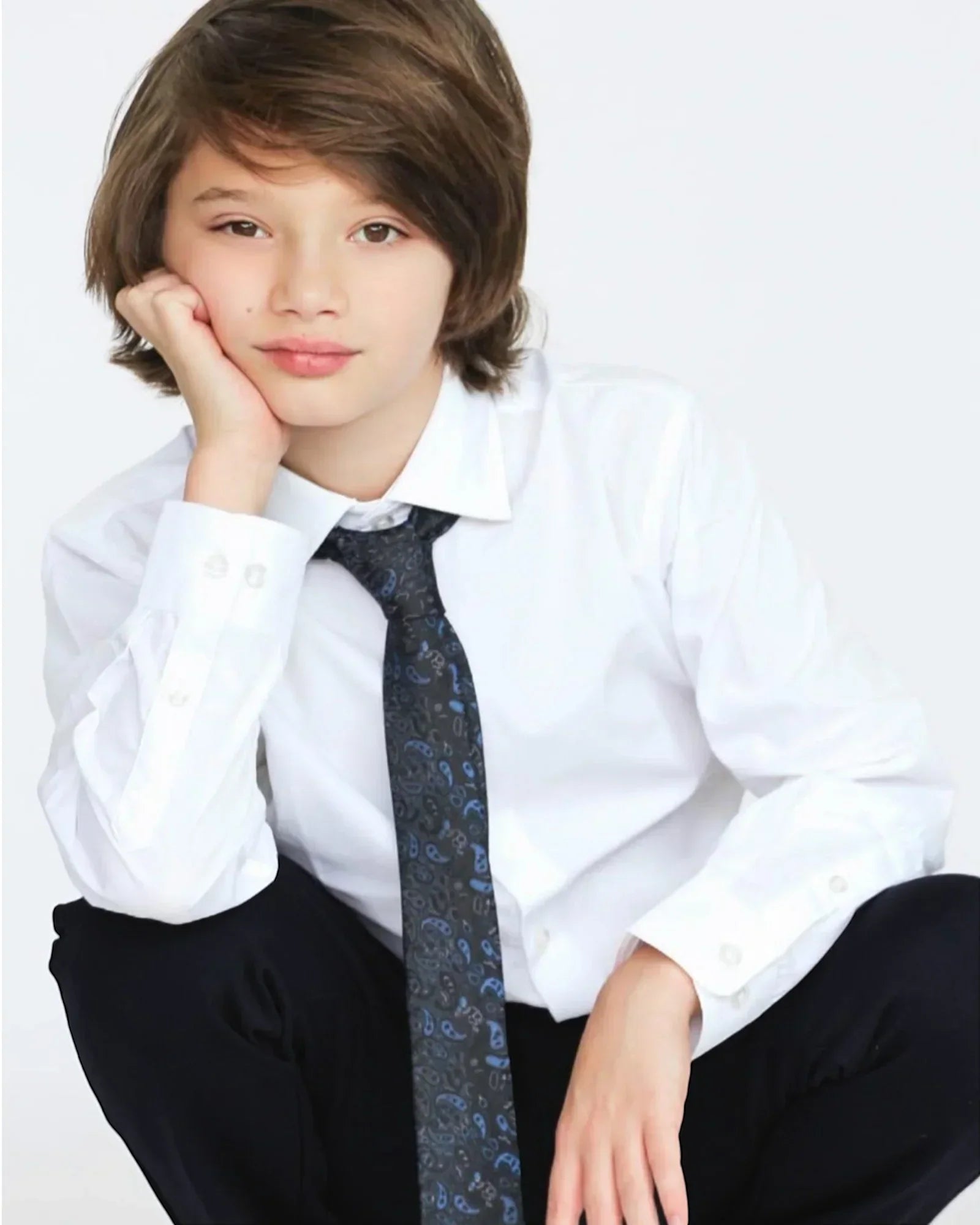 Young person wearing a white shirt and black tie with a neutral background