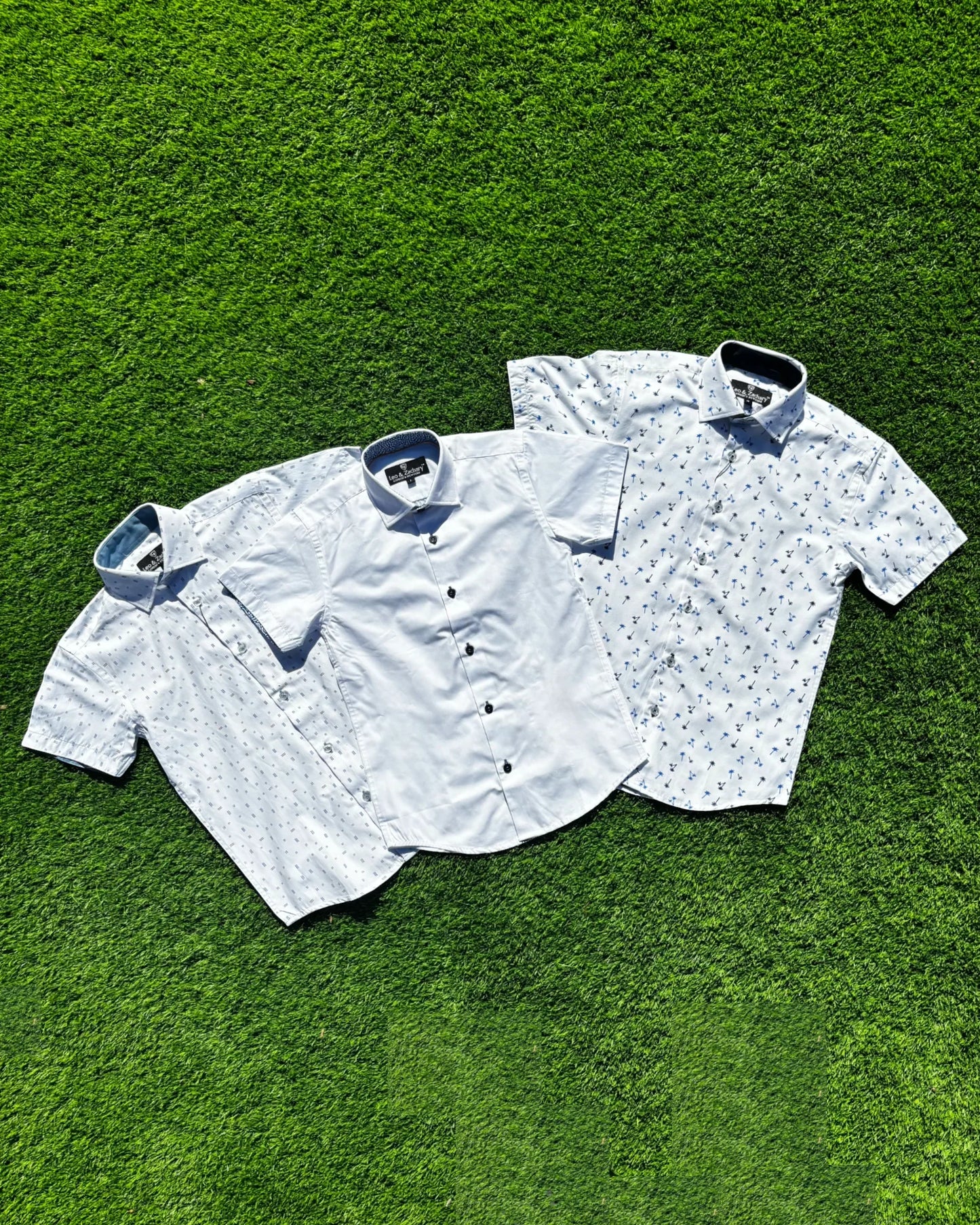 Three short-sleeve shirts on a green grass background
