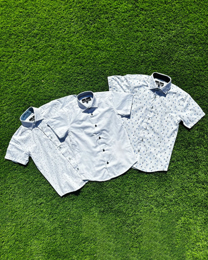 Three short-sleeve shirts on a green grass background
